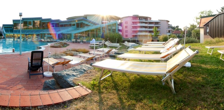 Poolbereich, © Vivea Ein Poolbereich mit Liegestühlen und einem modernen Gebäude im Hintergrund.