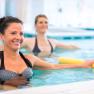 therapy_water_gymnastics_006_1170px, © Badener KurbetriebsgesmbH/Ulz Two women are doing aqua aerobics in a pool with yellow swimming noodles.