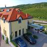 Aussenansicht Hotel Turmhof, © Hotel Turmhof Außenansicht des Hotel Turmhof mit roten Dächern und umliegenden Weinbergen.