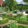 Garten Weinpension Andrea, © Weinpension Andrea Familie Schwertführer Ein gepflegter Garten mit Blumenbeeten, einem Sonnenschirm und Sitzbereich.