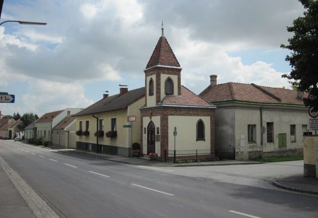 Lanzendorf, © Pop Werner Straße in Lanzendorf mit Kirche und Wohnhäusern.