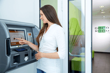 Good Rooms 2, © Good Rooms GmbH Frau bedient einen Check-in-Automaten in einem modernen Empfangsbereich.