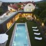 Außenbereich, © Hotel Landhaus Moserhof GmbH Luftaufnahme eines modernen Hauses mit Pool und Garten bei Abenddämmerung.