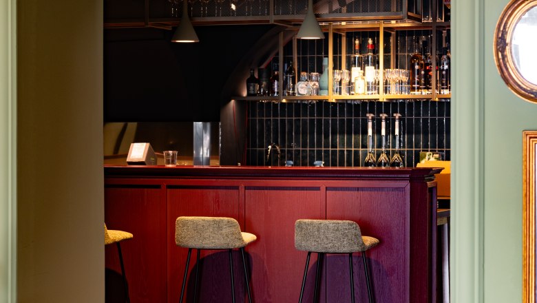 Stilvolles Ambiente, © thefirstthought Elegante Bar mit roten Holzmöbeln und hohen Stühlen.