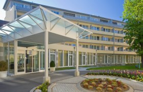 Innenhof, © Badener KurbetriebsgesmbH/Ulz Moderner Gebäudeeingang mit Glasdach und Garten.