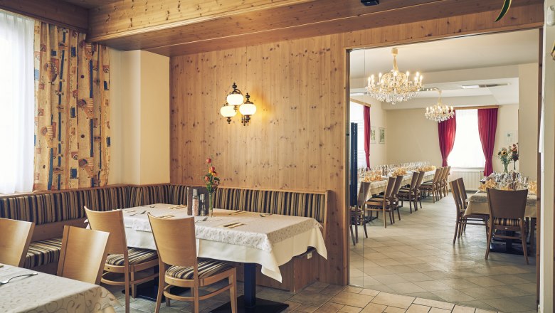 Gastzimmer und Festsaal, © Niederösterreich Werbung/Andreas Hofer Ein gemütliches Gastzimmer mit Holzwänden und ein angrenzender Festsaal mit Kronleuchtern und gedeckten Tischen.