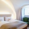 Thallern estate, © Freigut Thallern Cozy bedroom with double bed, green armchair and vaulted ceiling.