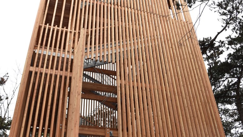 Theresienwarte, © 2016psb/sap Wooden tower with vertical slats and stairs, surrounded by trees.