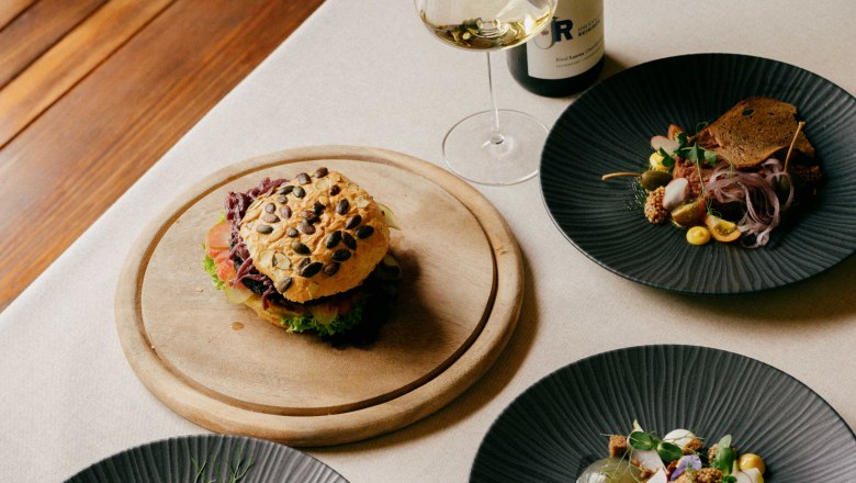 Ausgezeichnete Haubenküche, © Julius Hirtzberger Gourmet-Gerichte auf einem Tisch mit Wein.