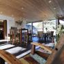 Frühstücksraum, © Hotel Landhaus Moserhof GmbH Ein moderner Frühstücksraum mit Holzmöbeln, großen Fenstern und einem Kronleuchter. Im Vordergrund ein Holzstuhl, im Hintergrund ein Esstisch.