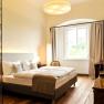Room, © Freigut Thallern Elegant hotel room with double bed, wooden floor and large window.