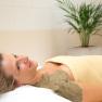 Sulphur mud pack, © Badener KurbetriebsgesmbH/Ulz. Woman relaxing with a sulphur mud pack on her shoulder, wrapped in a blanket, in the wellness area with a plant in the background.