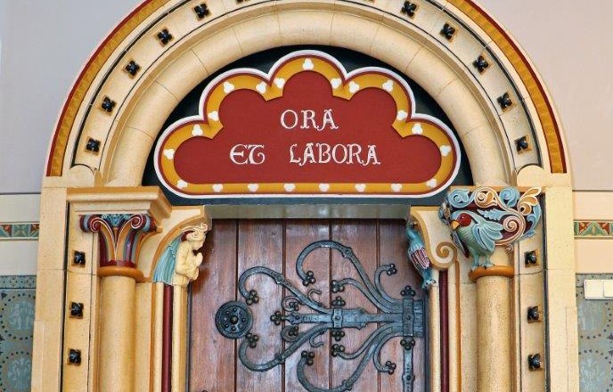Berndorf style classes, © holzinger.presse@gmx.at Decorated wooden door with Latin inscription 'Ora et Labora'.