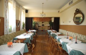 Gaststube, © Gasthof Smrcka Ein traditionelles Gasthaus mit Holzboden, gedeckten Tischen und einem Kronleuchter.