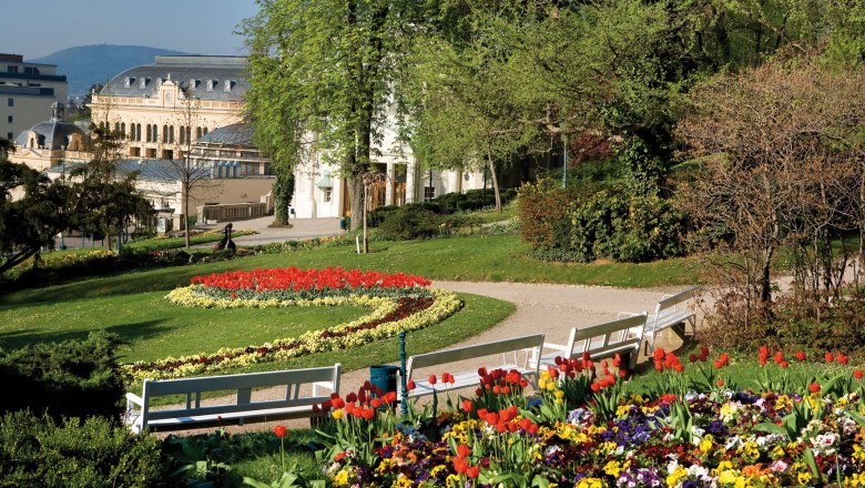Baden Spa Park, © Lois Lammerhuber Baden spa gardens with flowerbeds in bloom, benches and a historic building in the background.