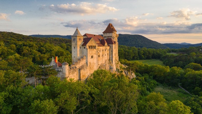 Liechtenstein Castle, © Burg Liechtenstein Betrieb GmbH Liechtenstein Castle in the middle of green forests at sunset.