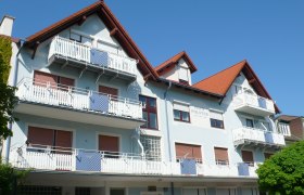 Haus, © Ferienwohnung Polster Mehrstöckiges Gebäude mit blauer Fassade und roten Dächern.