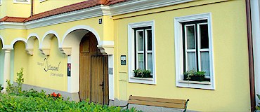 Gelbes Geb&auml;ude mit wei&szlig;en Fensterrahmen und Holzt&uuml;r.