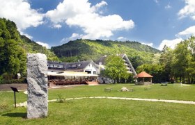 Hotel Krainerh&uuml;tte mit gr&uuml;ner Wiese und H&uuml;gel im Hintergrund.