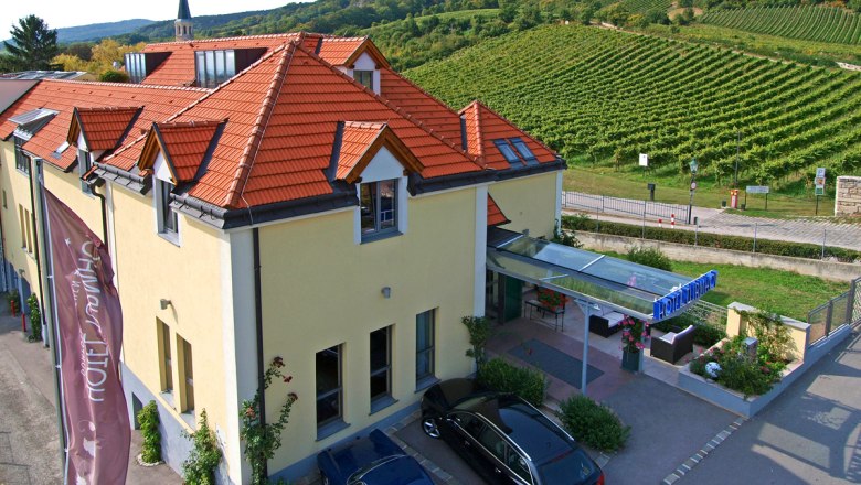 Au&szlig;enansicht des Hotel Turmhof mit roten D&auml;chern und umliegenden Weinbergen.