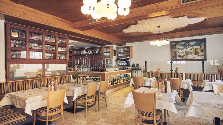 Innenansicht eines gemütlichen Restaurants mit Holzmöbeln und dekorativen Leuchten.