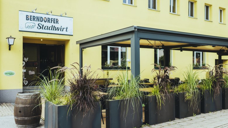 Entrance to the Berndorfer Stadtwirt with covered garden and plants.