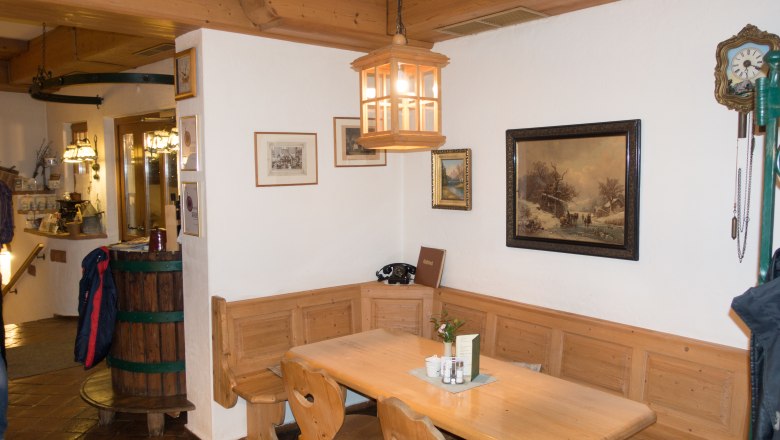 Gem&uuml;tliche Holzecke in einem traditionellen Gasthaus mit Tisch, St&uuml;hlen und Wanddekorationen.