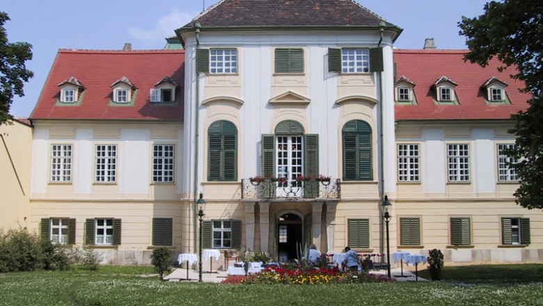 Front view of Hunyadi Palace with garden and flower beds.