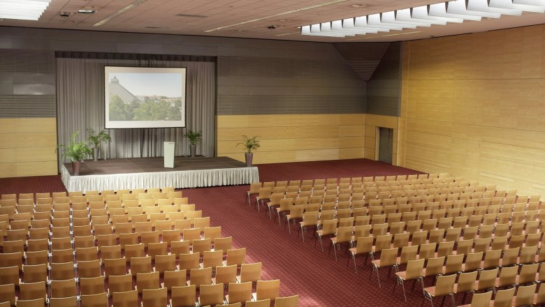 Gro&szlig;er Konferenzsaal mit B&uuml;hne und Stuhlreihen.