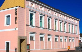 Ein rosa Geb&auml;ude mit der Aufschrift 'Hotel' an der Fassade.