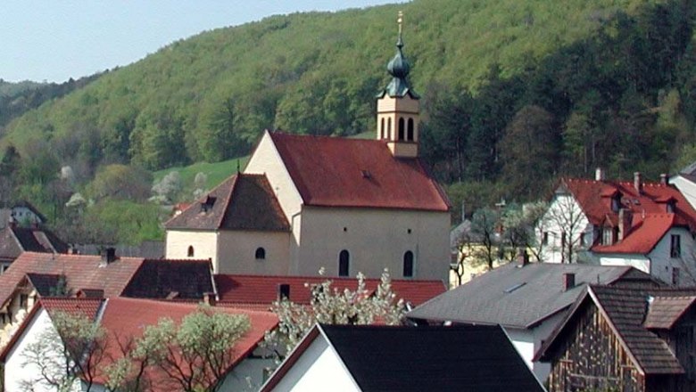 Wallfahrtskirche Maria Raisenmarkt in einer ländlichen Umgebung mit Hügeln im Hintergrund.