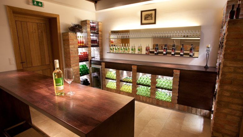 Interior view of a stylish wine shop with wine bottles and glasses on shelves.