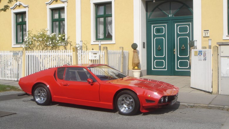 Yellow building with green door and red car.