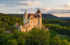 Burg Liechtenstein inmitten grüner Wälder bei Sonnenuntergang.