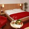 A cozy double room with a red armchair, bouquet of flowers and champagne on a table.