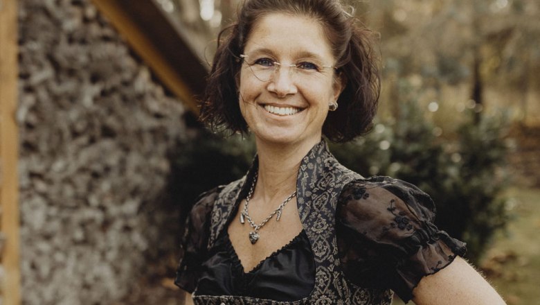 Frau in traditioneller Kleidung l&auml;chelt im Freien.