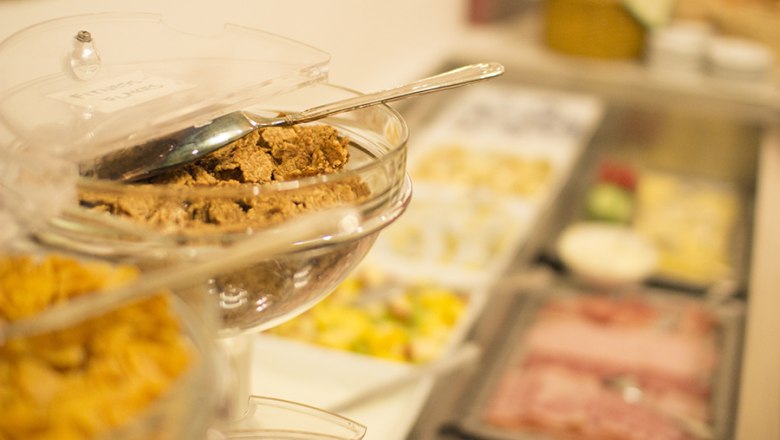 Ein Frühstücksbüffet mit Müsli, Aufschnitt und Obst.