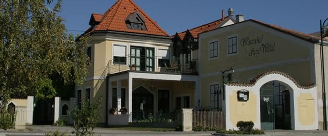 Ein traditionelles Geb&auml;ude mit gelber Fassade und rotem Ziegeldach, beschriftet mit 'Winzerhof zum Wald'.