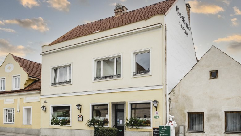 Gelbes Gasthaus mit Schildern und Blumen in Berndorf.