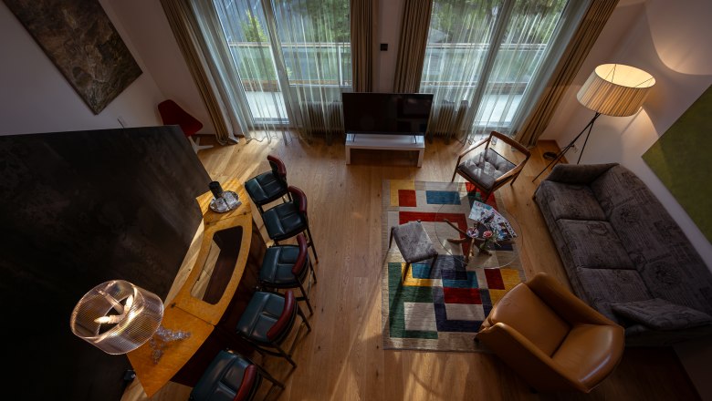 Living room with modern furnishings, colorful carpet and large windows.