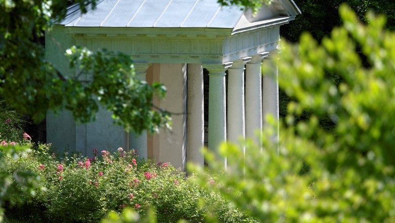 The Mozart Temple in Baden Kurpark, surrounded by green trees and flowering shrubs.