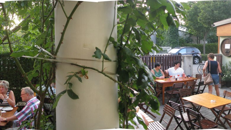 Gartenrestaurant mit Holztischen und G&auml;sten im Freien.