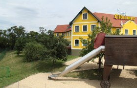 Gelbes Gebäude mit rotem Dach und Rutsche im Vordergrund.
