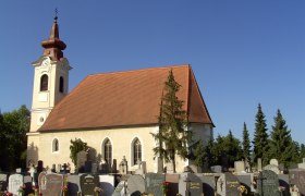 Au&szlig;enansicht einer Kirche mit Friedhof im Vordergrund und blauem Himmel.