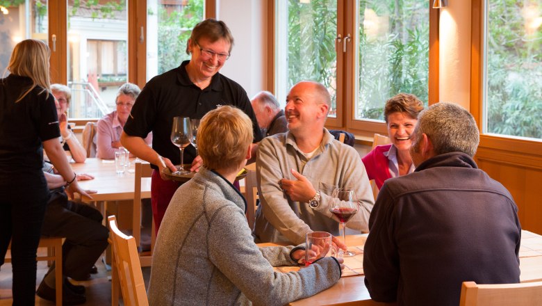 Menschen in einem gemütlichen Restaurant, die Wein trinken und lachen.