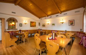 Gem&uuml;tliche Stube mit Holzm&ouml;beln, karierten Kissen und Wanddekorationen.