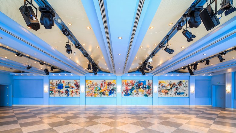 Innenansicht des Badener Saals im Congress Center Baden mit blauer Decke, bunten Wandgemälden und diagonalen Bodenfliesen.