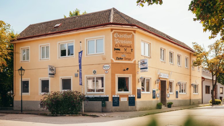 Ein gelbes zweistöckiges Gebäude mit der Aufschrift 'Gasthof Pension G. Martinek'.