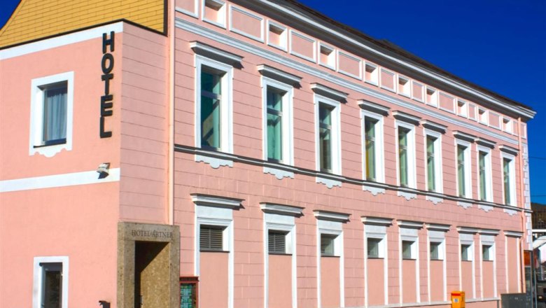 A pink building with the word 'Hotel' on the façade.