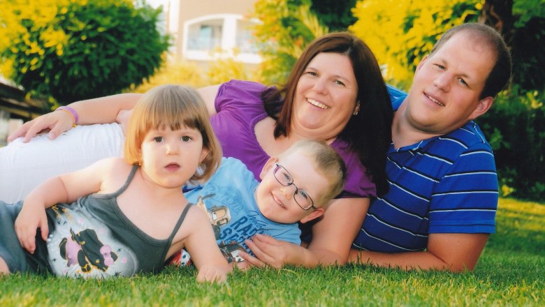 Eine Familie liegt l&auml;chelnd auf einer Wiese, bestehend aus zwei Erwachsenen und zwei Kindern.